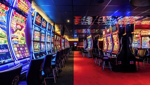 Una hilera de máquinas tragamonedas en un casino con un pasillo de alfombra roja.