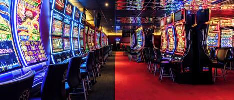 Una hilera de máquinas tragamonedas en un casino con un pasillo de alfombra roja.