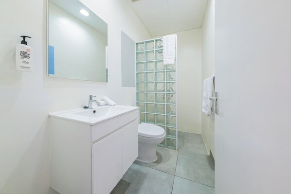 A modern bathroom with a white sink, mirror, and toilet.