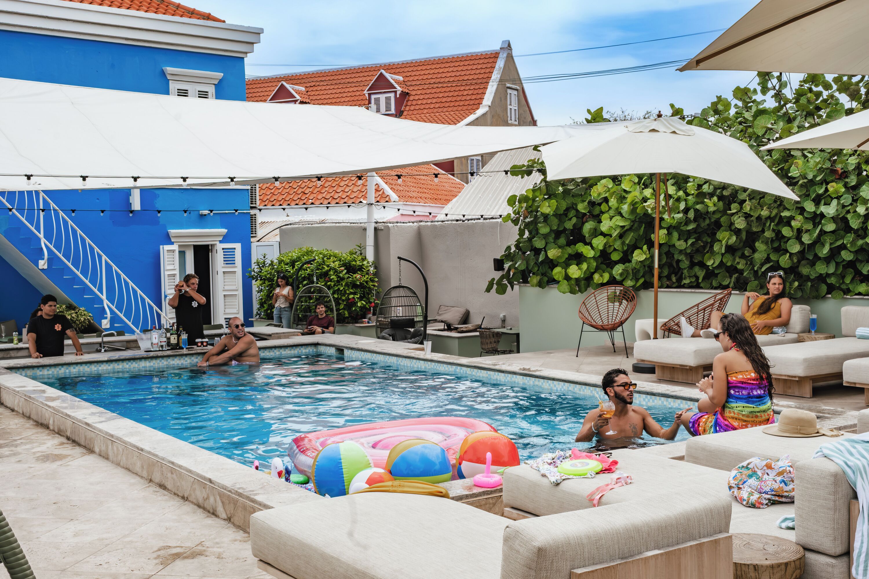 A swimming pool area with lounge chairs, a colorful inflatable float, and a staircase leading to a door.