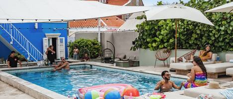 A swimming pool area with lounge chairs, a colorful inflatable float, and a staircase leading to a door.