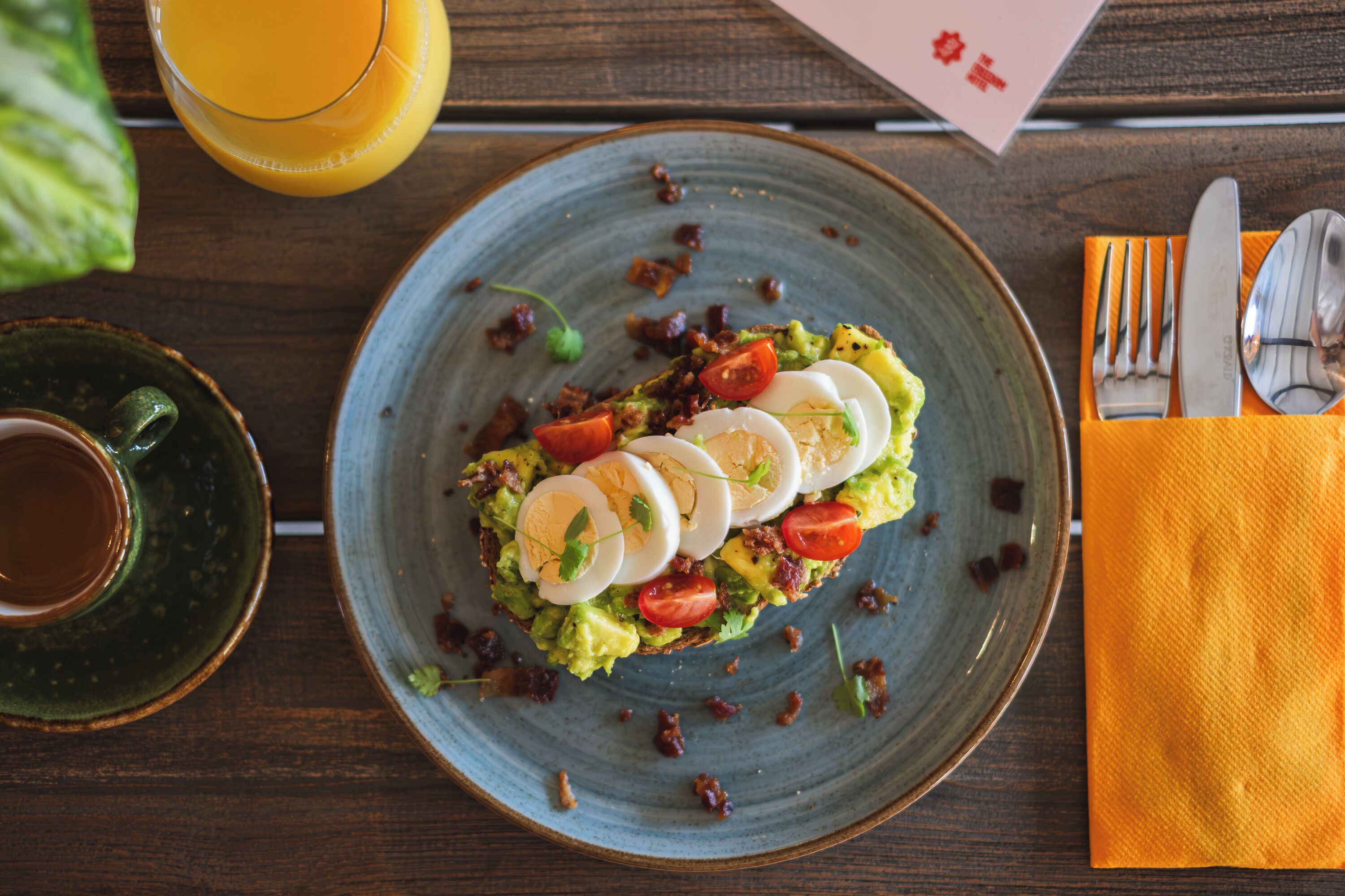 A plate of food with eggs, tomatoes, and greens on a blue plate.