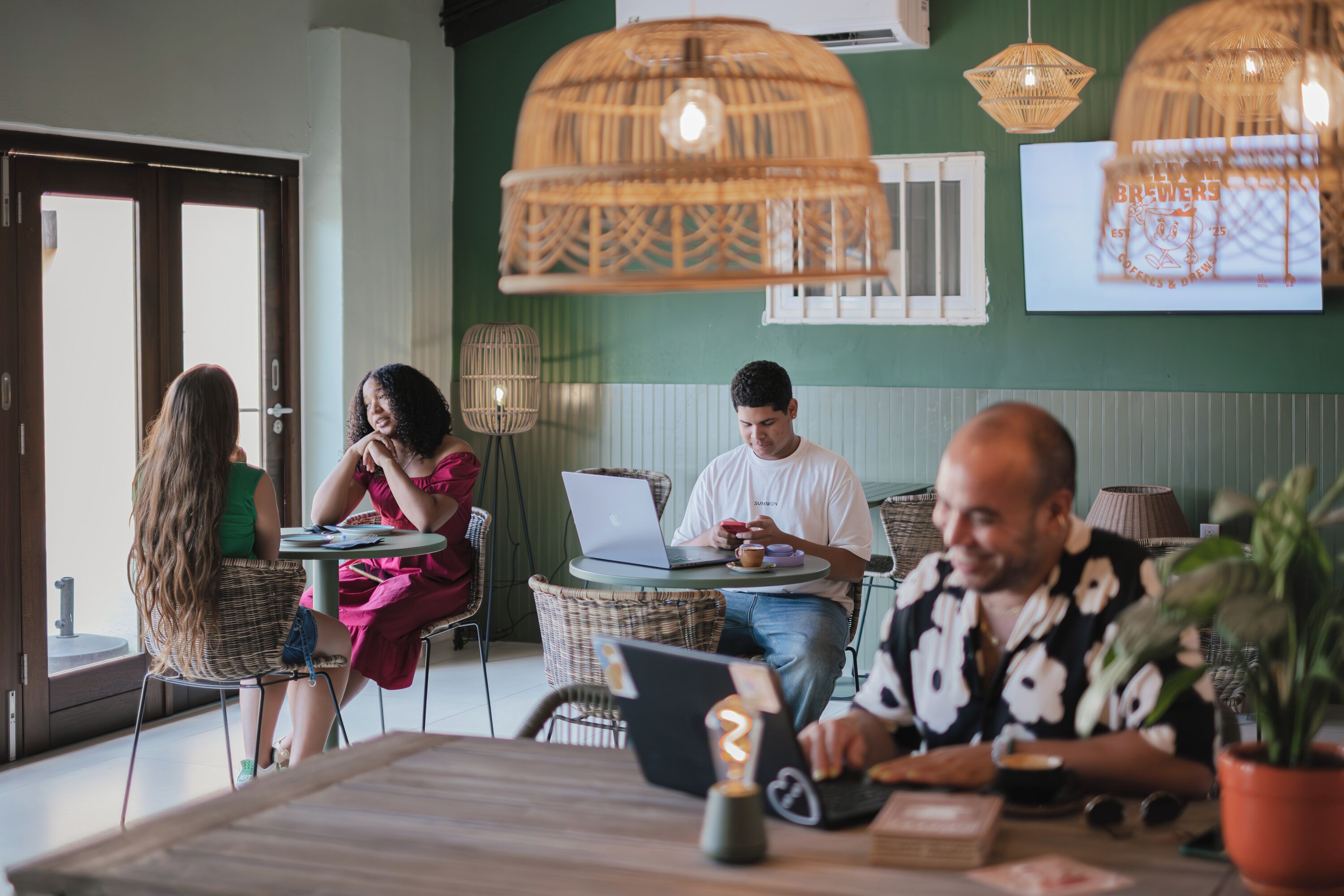 A cafe with wicker furniture, a laptop, and a potted plant.