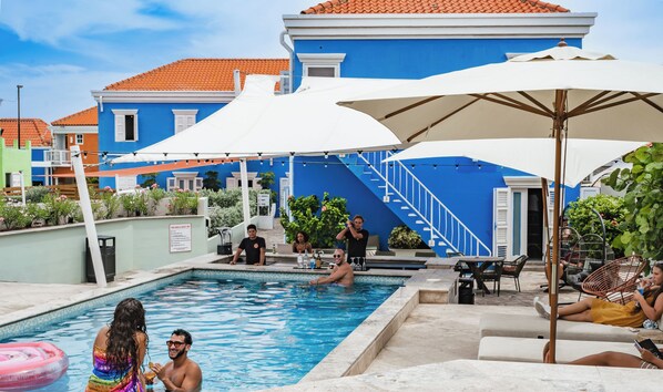 Una piscina al aire libre, sombrillas, sillones reclinables de piscina