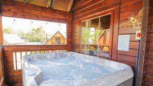 A wooden cabin with a hot tub on a balcony. - Sun View Lodge (Llanbedr)
