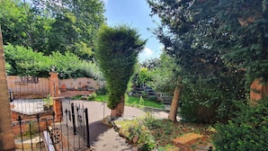 A paved pathway leading to a gated entrance with a brick wall and metal gate.