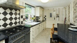 A kitchen with white cabinets, a black and white checkered backsplash, a gas stove, and a sink.