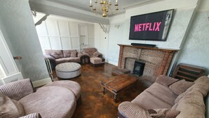 A living room with a fireplace, a television displaying 'NETFLIX', and a large window.