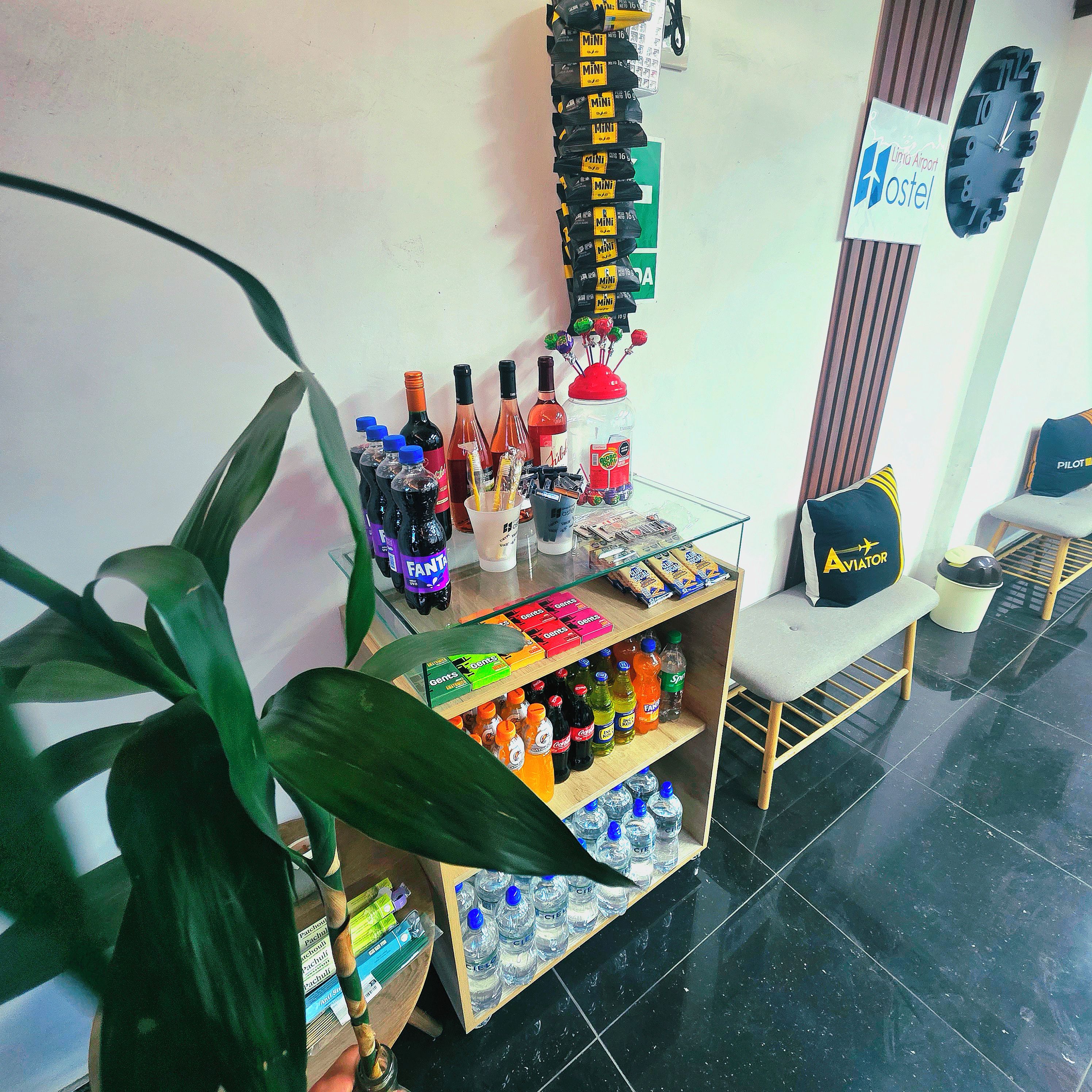 A reception area with a counter displaying various beverages and snacks, a clock, and a sign for a hostel.