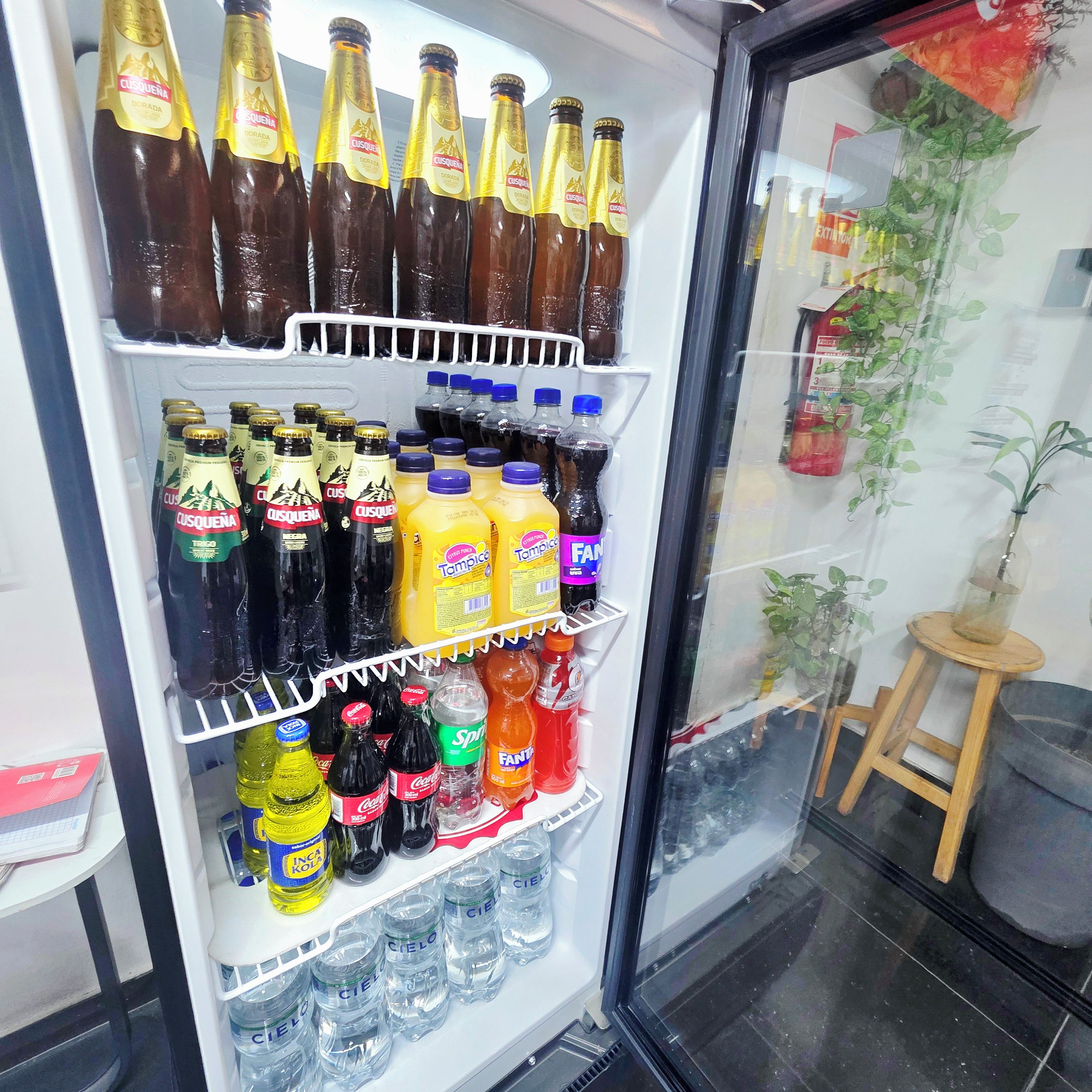 A beverage refrigerator stocked with various drinks including bottled water, sodas, and alcoholic beverages.