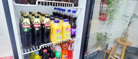 A beverage refrigerator stocked with various drinks including bottled water, sodas, and alcoholic beverages.
