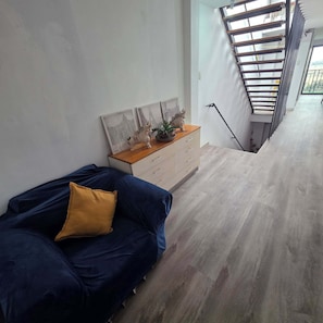 A bedroom with a bed, a nightstand, and a staircase leading to an upper level. - Lima Airport Hostel (Callao)