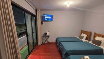Une chambre d’hôtel avec deux lits, une télévision, une petite table et une vue sur l’extérieur, accessible par une porte coulissante.