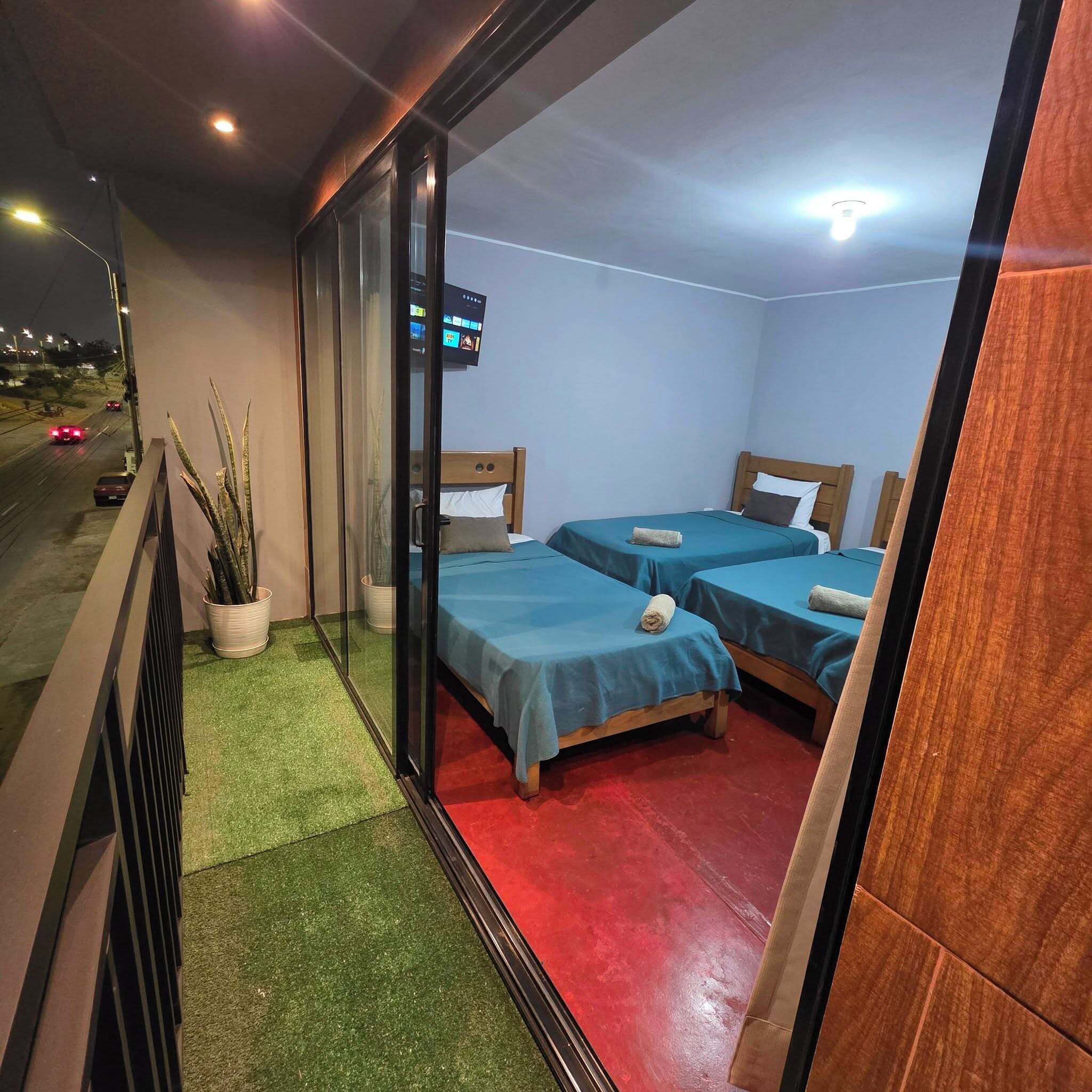 A room with two beds, a TV, and a view of the street.