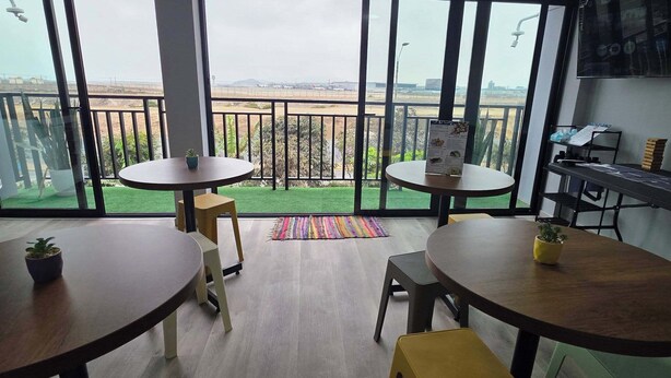 Una habitación moderna con dos mesas redondas, un taburete pequeño y una planta en maceta.
