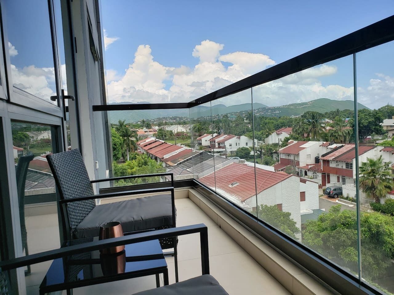 Un balcon donnant sur un quartier résidentiel, avec une chaise et une table.
