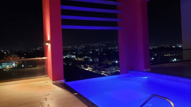 A rooftop pool with a city view at night. - 24/7 Security, 2B/R Paradise w/Infinity Rooftop Pool & City Views 🌴🏊 (Kingston 10)