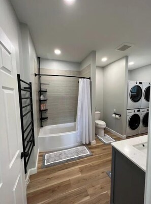 Bathroom features a bathtub, toilet, and wall-mounted washing machines.