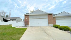 A residential house with a garage, a front lawn, and a driveway. - The Hideout-Single Level 2BR/2BA Townhouse near Highland! (Pocatello)
