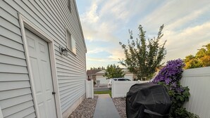 A covered outdoor area with a metal ramp leading to a building entrance, surrounded by gravel and a white fence. - The Hideout-Single Level 2BR/2BA Townhouse near Highland! (Pocatello)