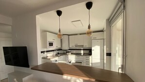A modern kitchen with white cabinets, a wooden island, and pendant lighting. - Duplex penthouse facing the sea (Marbella)
