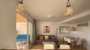 A modern living room with a sofa, coffee table, and dining area. - Duplex penthouse facing the sea (Marbella)