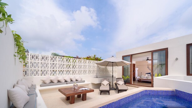 A modern outdoor living area with a pool, seating, and a sliding glass door leading to a bedroom.