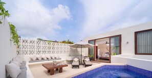 A modern outdoor living area with a pool, seating, and a sliding glass door leading to a bedroom. - K'uyen Boutique Hotel (Tulum)