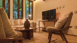 A modern living room with a sofa, armchairs, a coffee table, and a TV on a stand.
