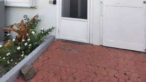 A white building with a red-tiled roof, a white door with a glass panel, and a small window with a white frame. - North Finger Private Villa in Paradise (Jolly Harbour)