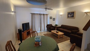 A living room with a TV, sofa, and dining table. - North Finger Private Villa in Paradise (Jolly Harbour)