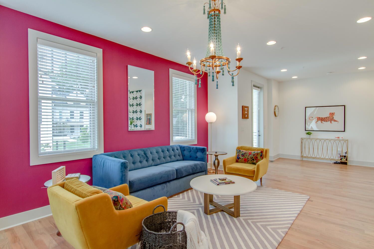 A modern living room with a blue sofa, yellow armchairs, a white coffee table, and a chandelier.