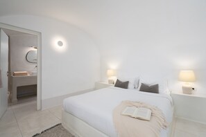 Une chambre à coucher avec un grand lit, des lampes de chevet, une table de chevet et une porte donnant sur une salle de bain.