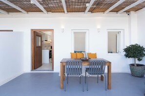 Un coin repas avec une table et des chaises en bois, une plante en pot et une vue sur la cuisine.