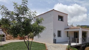 A modern two-story house with a white exterior, a small balcony, and a well-maintained lawn.
