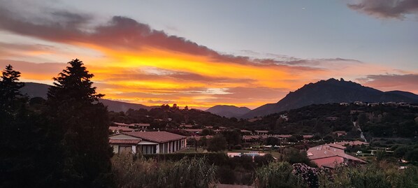 Um pôr do sol sobre uma paisagem montanhosa com uma aldeia abaixo.