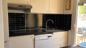 A kitchen with white cabinets, a black countertop, a dishwasher, and a stainless steel range hood. - Detached villa in residential area, beach and shops nearby (Sanary-sur-Mer)