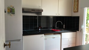 A compact kitchen with white cabinets, a black backsplash, and a stainless steel range hood. - Detached villa in residential area, beach and shops nearby (Sanary-sur-Mer)