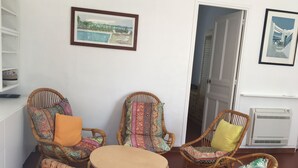 A room with wicker furniture, a small round table, and two framed pictures on the wall. - Detached villa in residential area, beach and shops nearby (Sanary-sur-Mer)