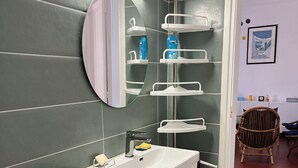 A bathroom with a white sink, mirror, and shelves with toiletries. - Detached villa in residential area, beach and shops nearby (Sanary-sur-Mer)