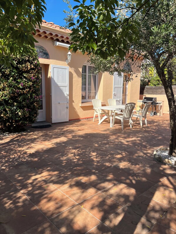A patio area with a tiled floor, white chairs, and a table.