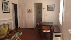 A room with a dining table, wicker chairs, a radiator, and framed pictures on the walls. - Detached villa in residential area, beach and shops nearby (Sanary-sur-Mer)