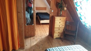 Une pièce en bois avec un lit, une commode et un miroir dans lequel on peut voir le reflet d’une personne.