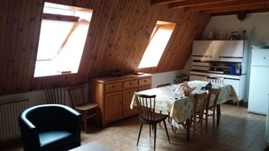 Une cuisine avec des meubles de rangement en bois, une table à manger avec des chaises et un réfrigérateur.