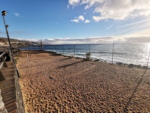 A beach with a wooden boardwalk, a netted area for volleyball, and a view of the ocean. - Home2Book Caletillas Breeze & Comfort (Tenerife)