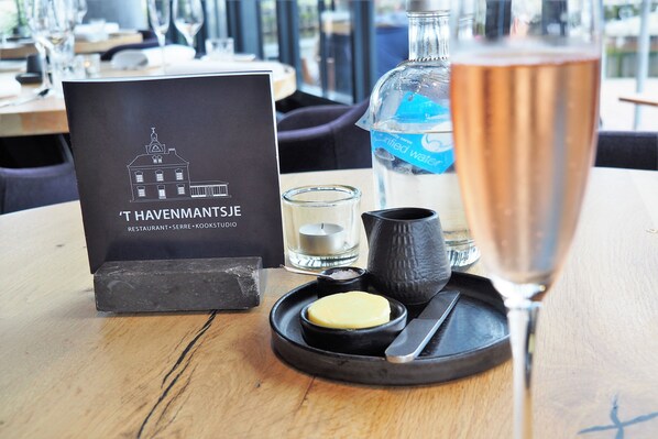 A table with a menu, a bottle of water, a candle, a small bowl with butter, and a knife.