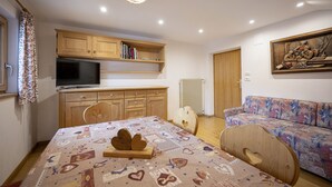 Une pièce confortable avec un lit, une télévision, des meubles en bois, un canapé et un luminaire au plafond.