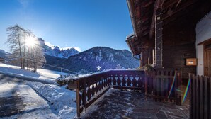 Un bâtiment en bois, doté d’une entrée pavée de pierres, d’une clôture en bois et offrant une vue sur des montagnes enneigées.