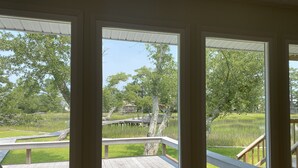 Ein Zimmer mit großen Fenstern, die auf eine Holzterrasse und einen Teich blicken.