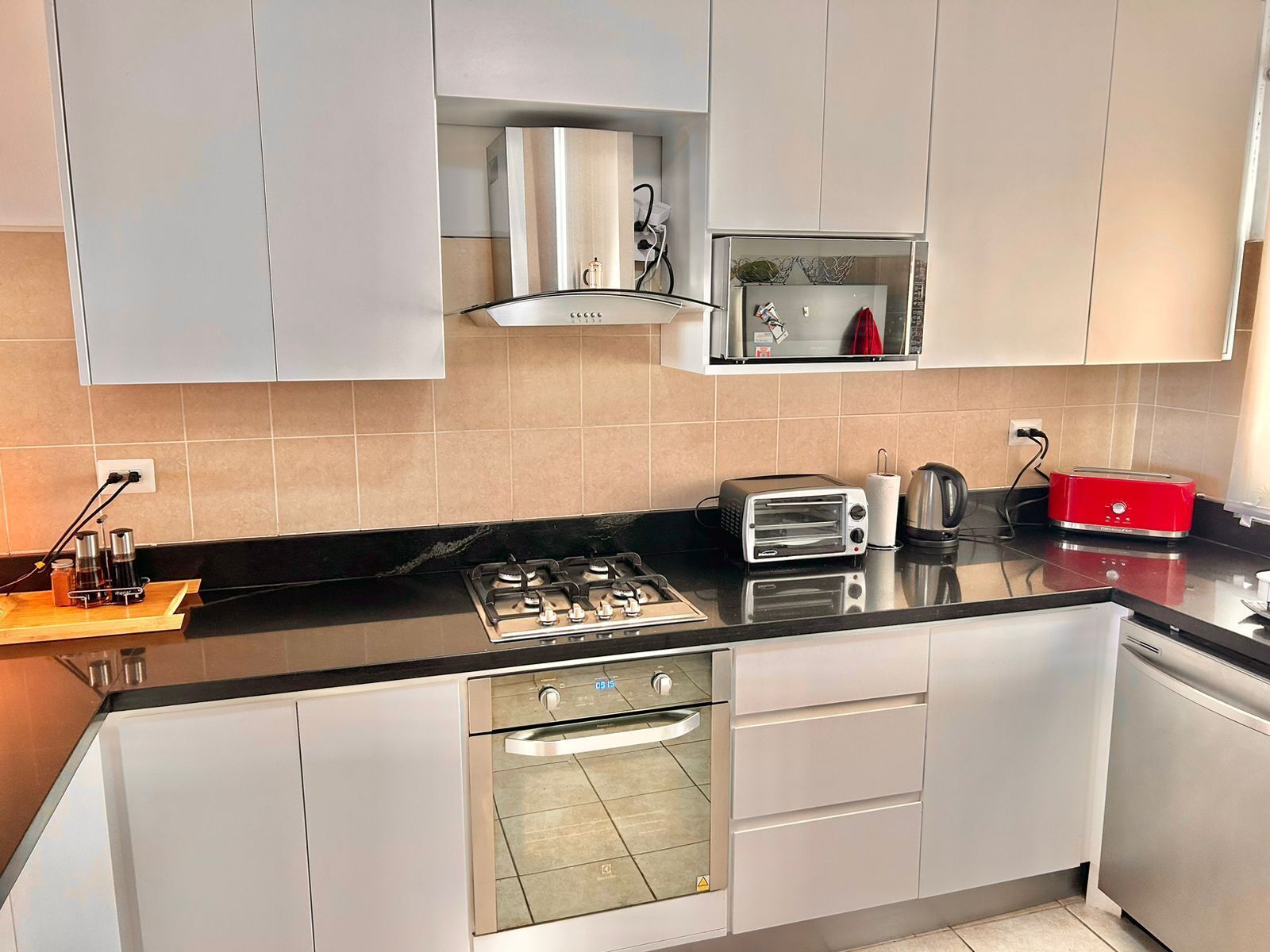 A modern kitchen with a gas stove, built-in oven, and a red toaster.